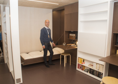 Michael Stenberg, fastighetschef Stångåstaden, visar hur det stora rummet får en ny planlösning. Med hjälp av flyttbara väggar och gardiner skapas tre mindre sovrum längs ena väggen.